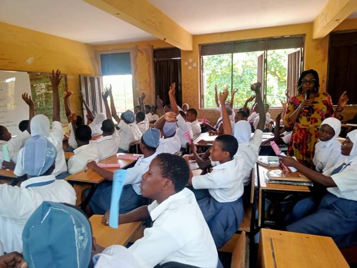 Nigerian girls in a classroom raising their hands during a leadership training