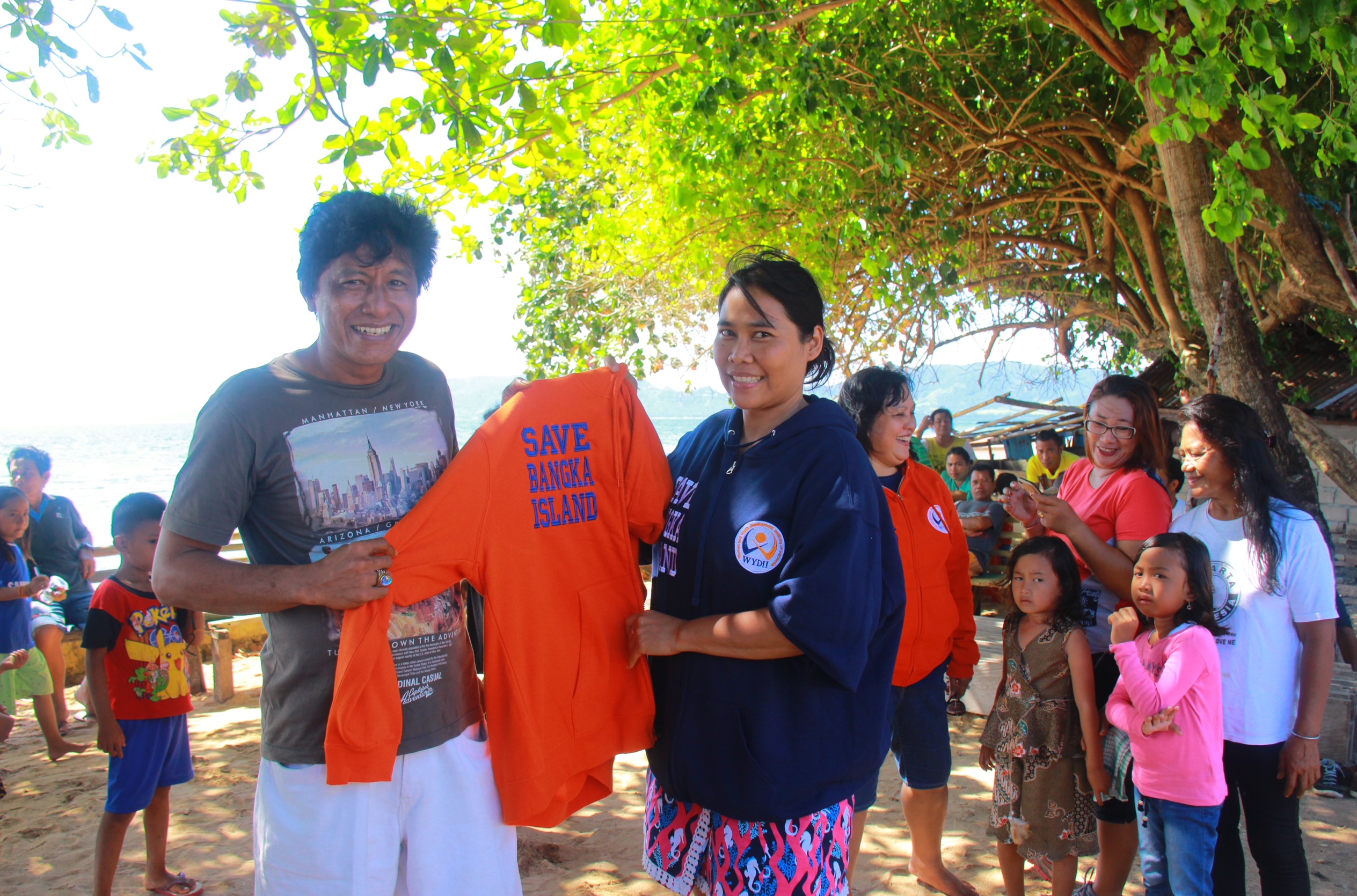 Indonesian lady holding up a shirt with the head of a village at Bangka Island