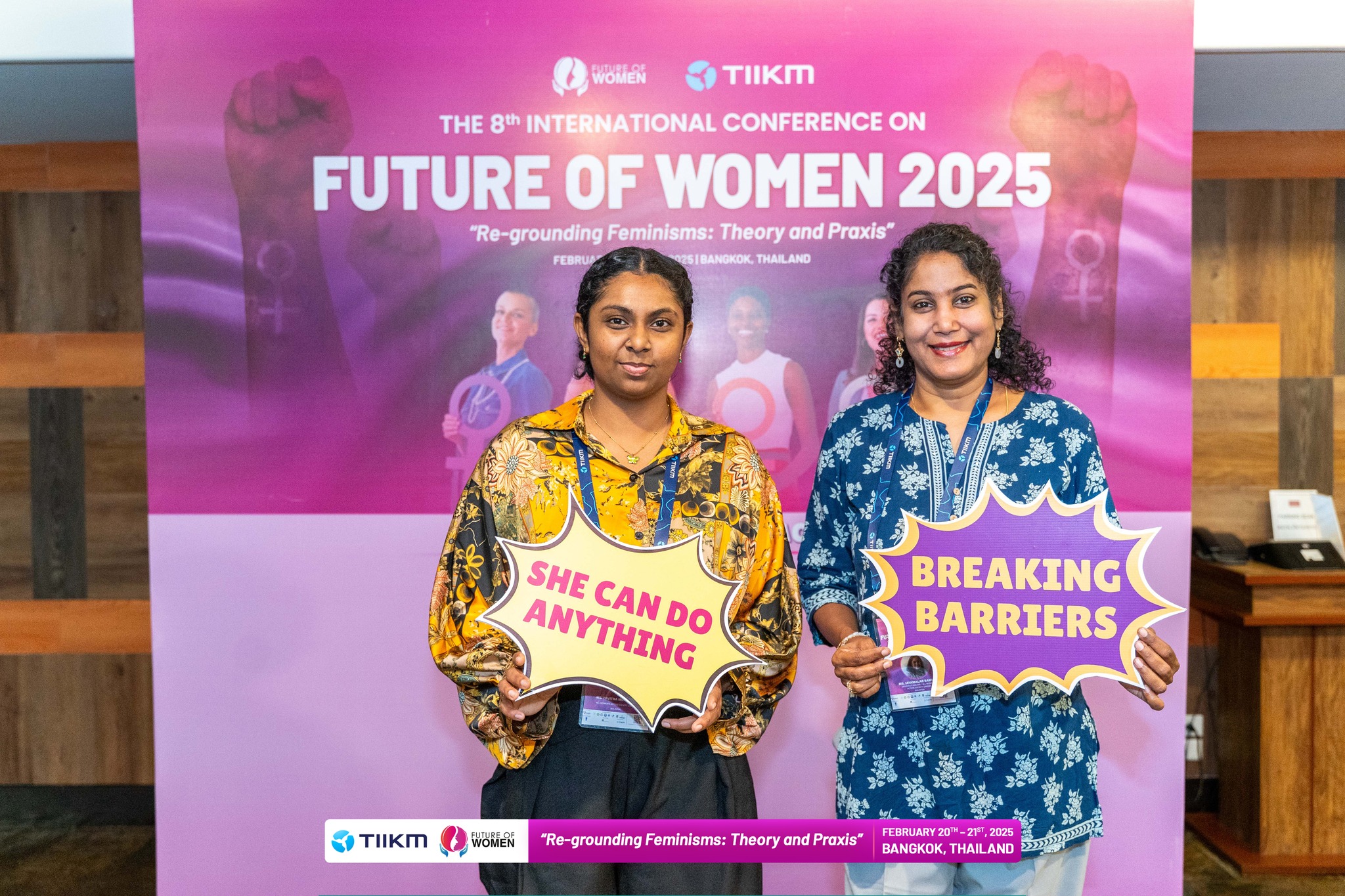 Two women from AWAM at the Future of Women Conference Holding Signs about Empowerment