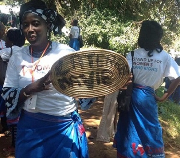 Julie Cissé standing up for rural women's rights to land with a sign that says, "My land, my life."