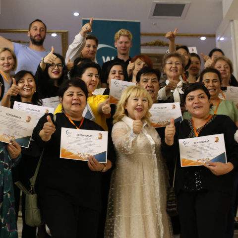 women from Kazakhstan with their thumbs up holding certificates